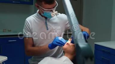 年轻牙医戴着医用手套、口罩和眼镜，用牙镜和牙坝`病人的牙齿